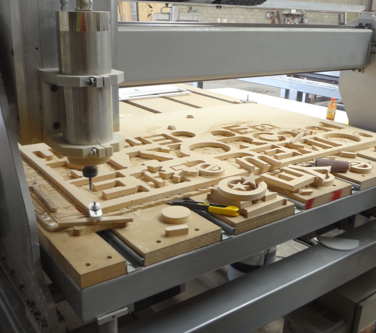 Router CNC cortando letras y piezas en una placa de MDF